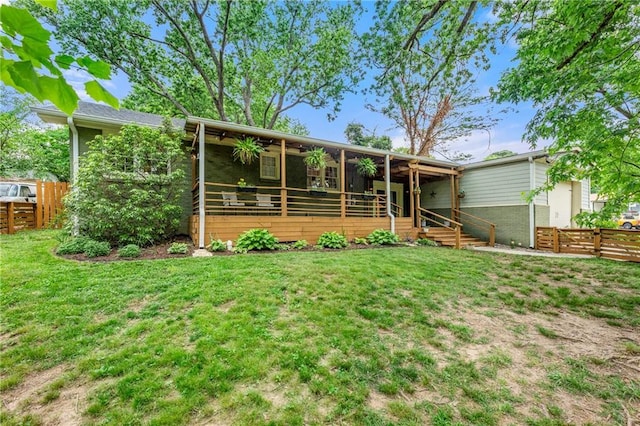 rear view of house featuring a ceiling fan, a yard, brick siding, and fence