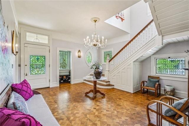 foyer entrance featuring stairway, plenty of natural light, and an inviting chandelier