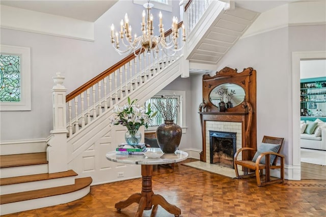 stairway with a notable chandelier and a fireplace with flush hearth