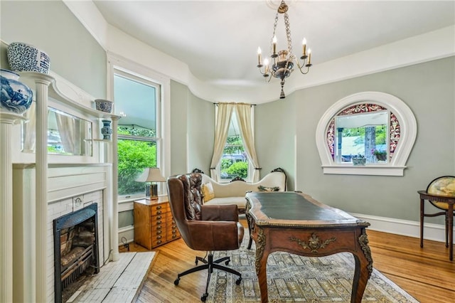 office featuring an inviting chandelier, baseboards, a fireplace, and wood finished floors