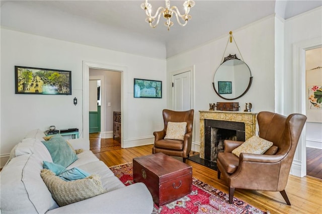 living room with baseboards, a fireplace, wood finished floors, and a notable chandelier