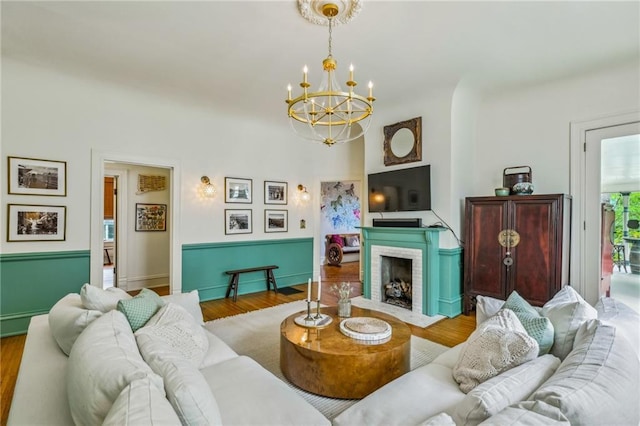 living room with a fireplace, wood finished floors, and a notable chandelier