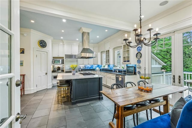 kitchen with an inviting chandelier, a center island, stainless steel appliances, island exhaust hood, and glass insert cabinets