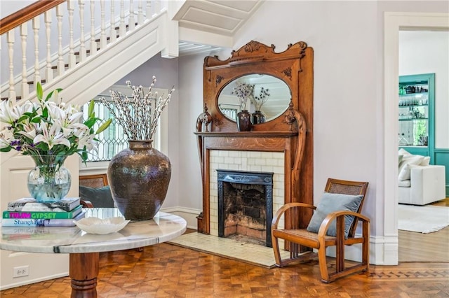 living area with a brick fireplace, baseboards, and stairs