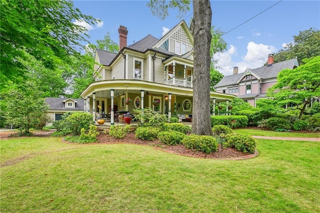 back of house featuring a lawn, covered porch, and a chimney