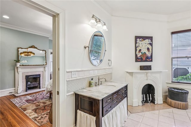 bathroom featuring crown molding, vanity, ensuite bathroom, a high end fireplace, and tasteful backsplash