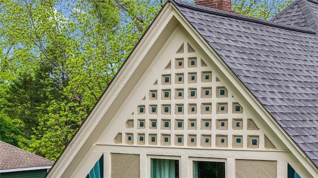 exterior details featuring a chimney and roof with shingles