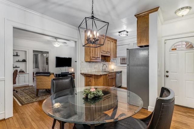 dining space featuring light wood finished floors, ceiling fan, and ornamental molding