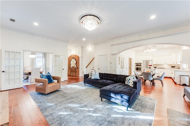 living room featuring light hardwood / wood-style flooring, ornamental molding, and an inviting chandelier