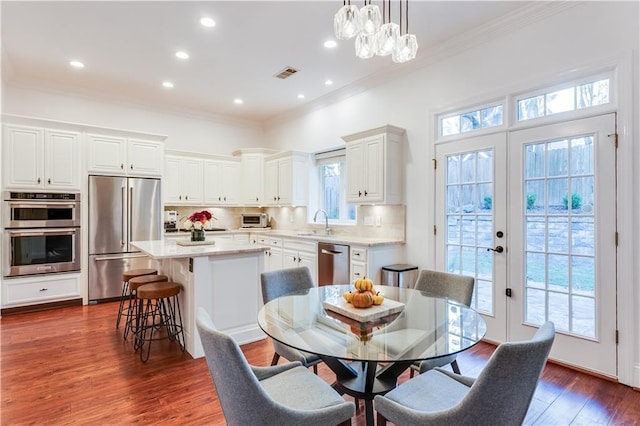 kitchen featuring a center island, tasteful backsplash, decorative light fixtures, white cabinets, and appliances with stainless steel finishes