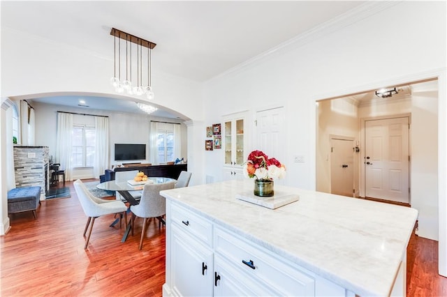 kitchen with crown molding, hardwood / wood-style flooring, decorative light fixtures, a kitchen island, and white cabinetry