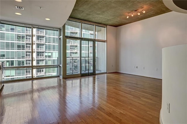 spare room with wood-type flooring and a wall of windows