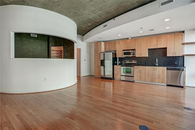 kitchen with stainless steel appliances, sink, light brown cabinetry, and light hardwood / wood-style floors