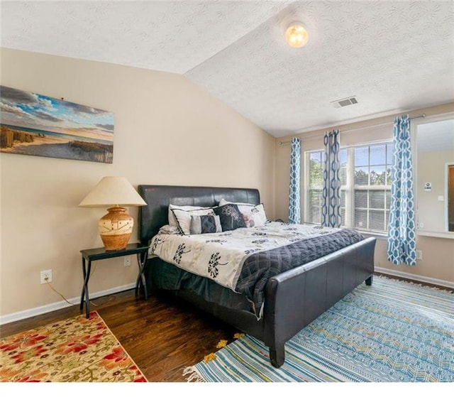 bedroom with a textured ceiling, dark wood-type flooring, and lofted ceiling