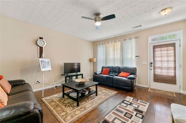 living room with a textured ceiling, dark hardwood / wood-style floors, and ceiling fan