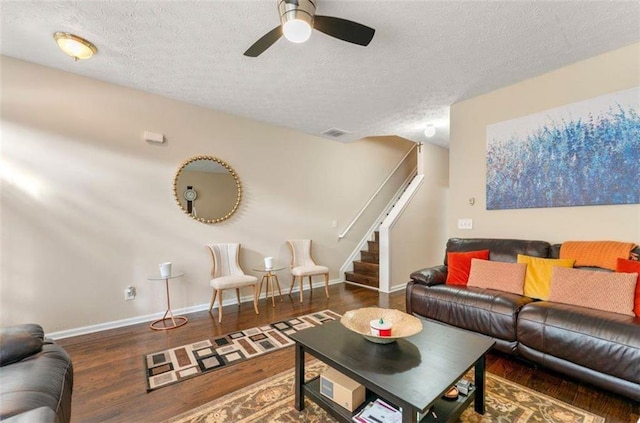 living room with a textured ceiling, dark hardwood / wood-style floors, and ceiling fan