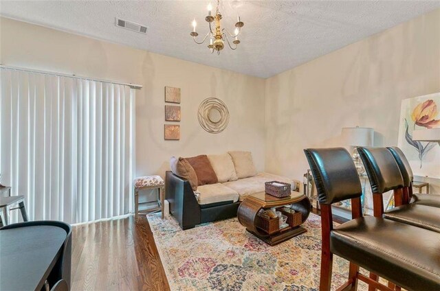 living room featuring a textured ceiling, dark hardwood / wood-style flooring, and a notable chandelier