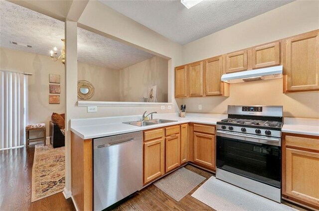 kitchen with a textured ceiling, stainless steel appliances, dark hardwood / wood-style floors, and sink