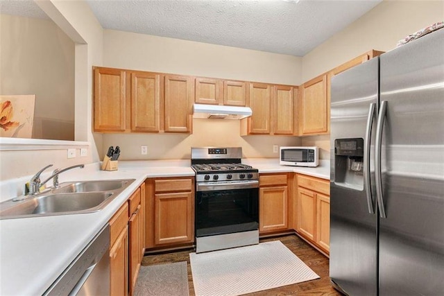 kitchen with sink, dark hardwood / wood-style floors, a textured ceiling, light brown cabinetry, and appliances with stainless steel finishes