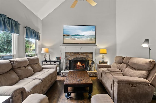 living room featuring lofted ceiling, ceiling fan, dark hardwood / wood-style floors, and a stone fireplace