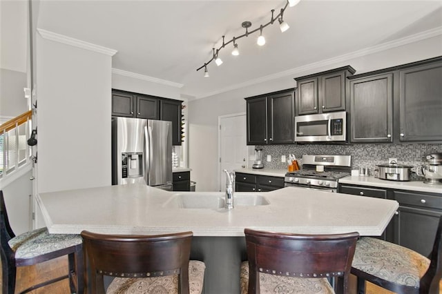 kitchen with sink, ornamental molding, tasteful backsplash, a breakfast bar, and appliances with stainless steel finishes