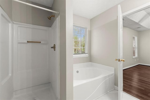 bathroom with separate shower and tub, hardwood / wood-style floors, and a textured ceiling