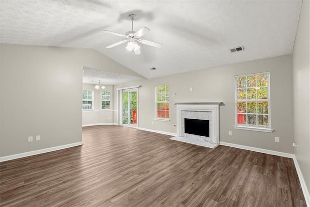 unfurnished living room with lofted ceiling, ceiling fan with notable chandelier, dark hardwood / wood-style floors, a fireplace, and a textured ceiling