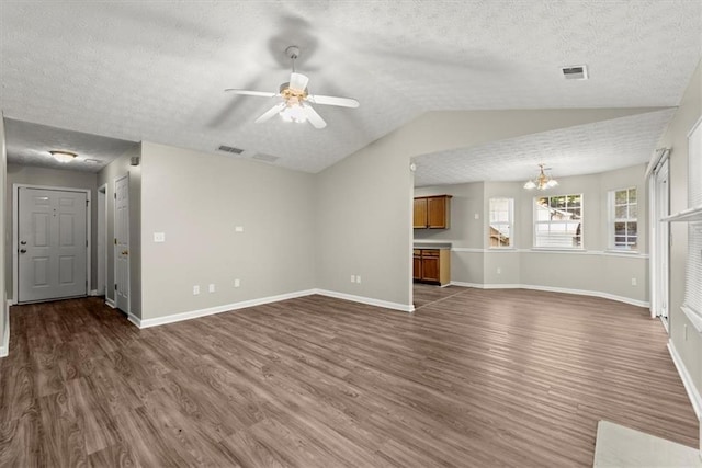 unfurnished living room featuring a textured ceiling, dark hardwood / wood-style flooring, ceiling fan with notable chandelier, and vaulted ceiling