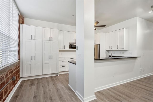 kitchen featuring ceiling fan, light hardwood / wood-style floors, white cabinetry, and brick wall