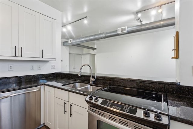 kitchen with appliances with stainless steel finishes, dark stone countertops, and white cabinetry