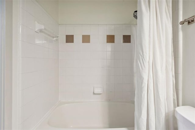 bathroom featuring toilet and shower / bath combination with curtain