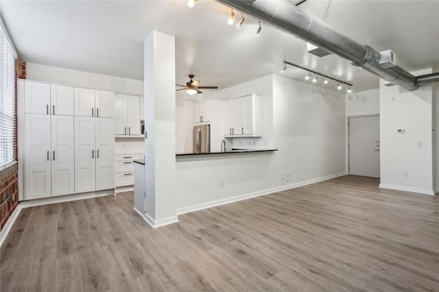 kitchen with stainless steel fridge, white cabinetry, and light hardwood / wood-style flooring