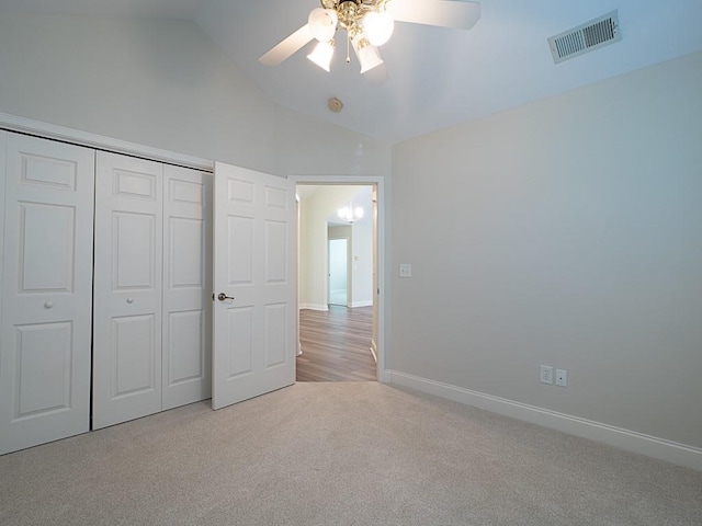 unfurnished bedroom with ceiling fan, a closet, light colored carpet, and lofted ceiling