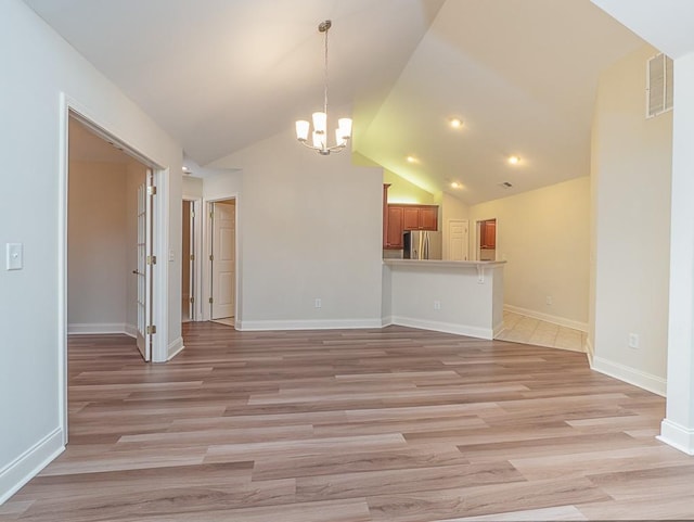 unfurnished living room featuring light hardwood / wood-style floors, vaulted ceiling, and a notable chandelier