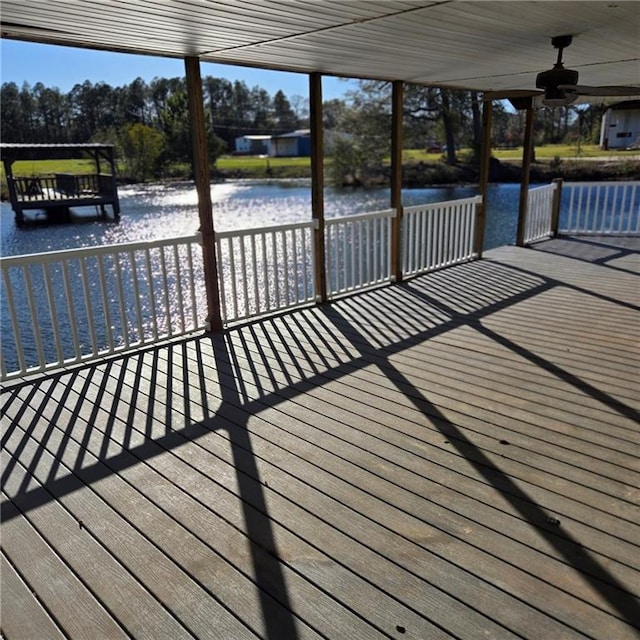 deck with ceiling fan and a water view