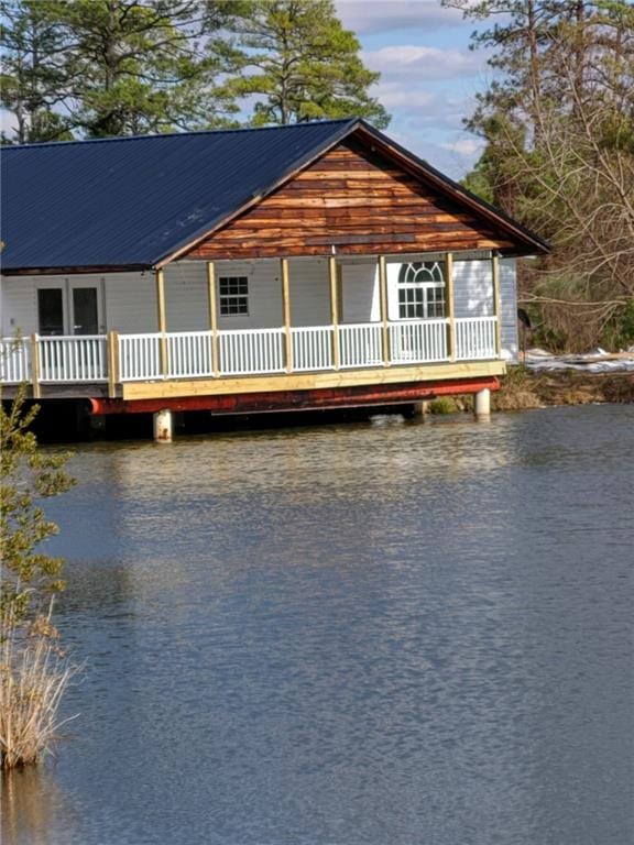 exterior space featuring a water view, metal roof, and driveway