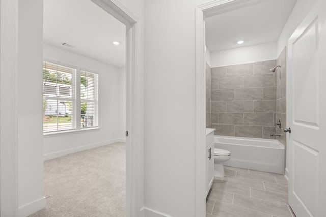 full bathroom featuring vanity, tiled shower / bath combo, and toilet