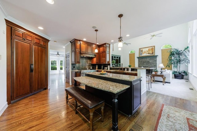 kitchen featuring a ceiling fan, a peninsula, wood finished floors, a sink, and recessed lighting