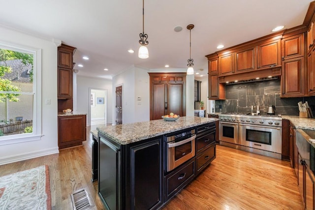 kitchen with high quality appliances, crown molding, light wood-style flooring, decorative light fixtures, and tasteful backsplash