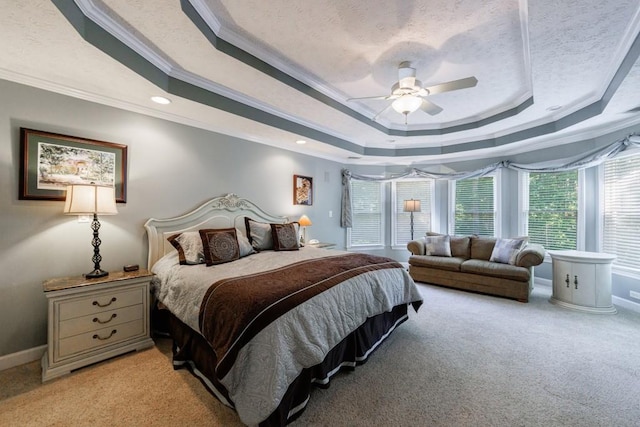 bedroom with a raised ceiling, crown molding, light colored carpet, ceiling fan, and baseboards