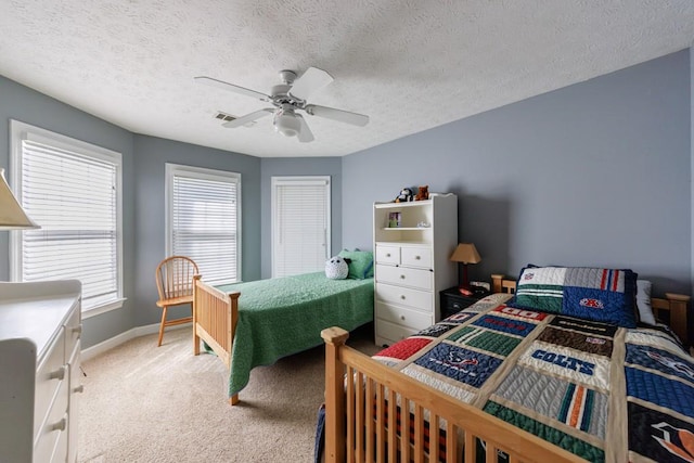 bedroom featuring light carpet, baseboards, ceiling fan, and a textured ceiling