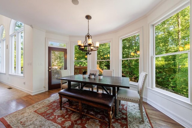 dining space with a chandelier, plenty of natural light, baseboards, crown molding, and wood finished floors