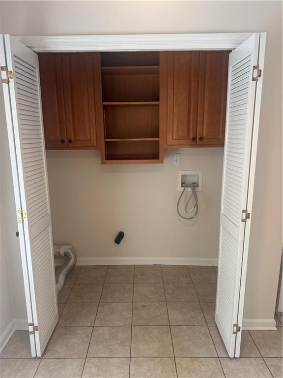 laundry room featuring hookup for a washing machine, light tile patterned flooring, and cabinets