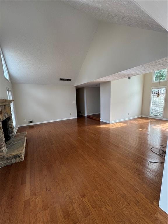 unfurnished living room with dark wood-type flooring, a fireplace, high vaulted ceiling, and a textured ceiling