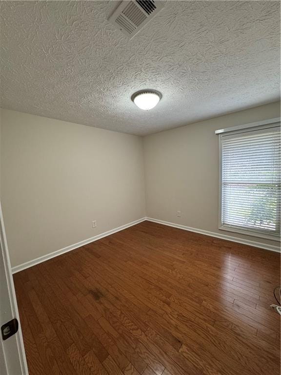 unfurnished room featuring dark hardwood / wood-style floors and a textured ceiling