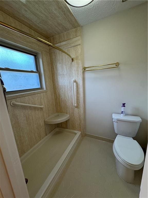 bathroom featuring toilet, a textured ceiling, and a shower