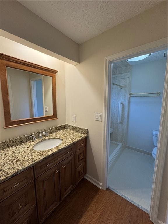 bathroom featuring hardwood / wood-style flooring, vanity, a textured ceiling, toilet, and walk in shower