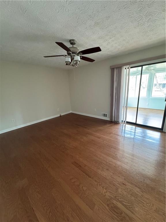 unfurnished room with ceiling fan, wood-type flooring, and a textured ceiling