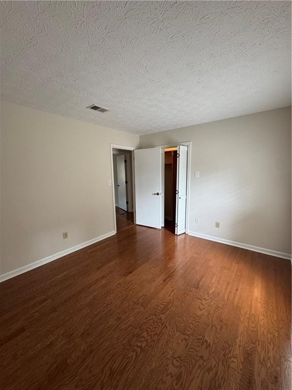 unfurnished room featuring dark hardwood / wood-style floors and a textured ceiling