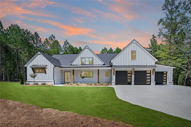 modern farmhouse style home with a garage, a porch, and a yard